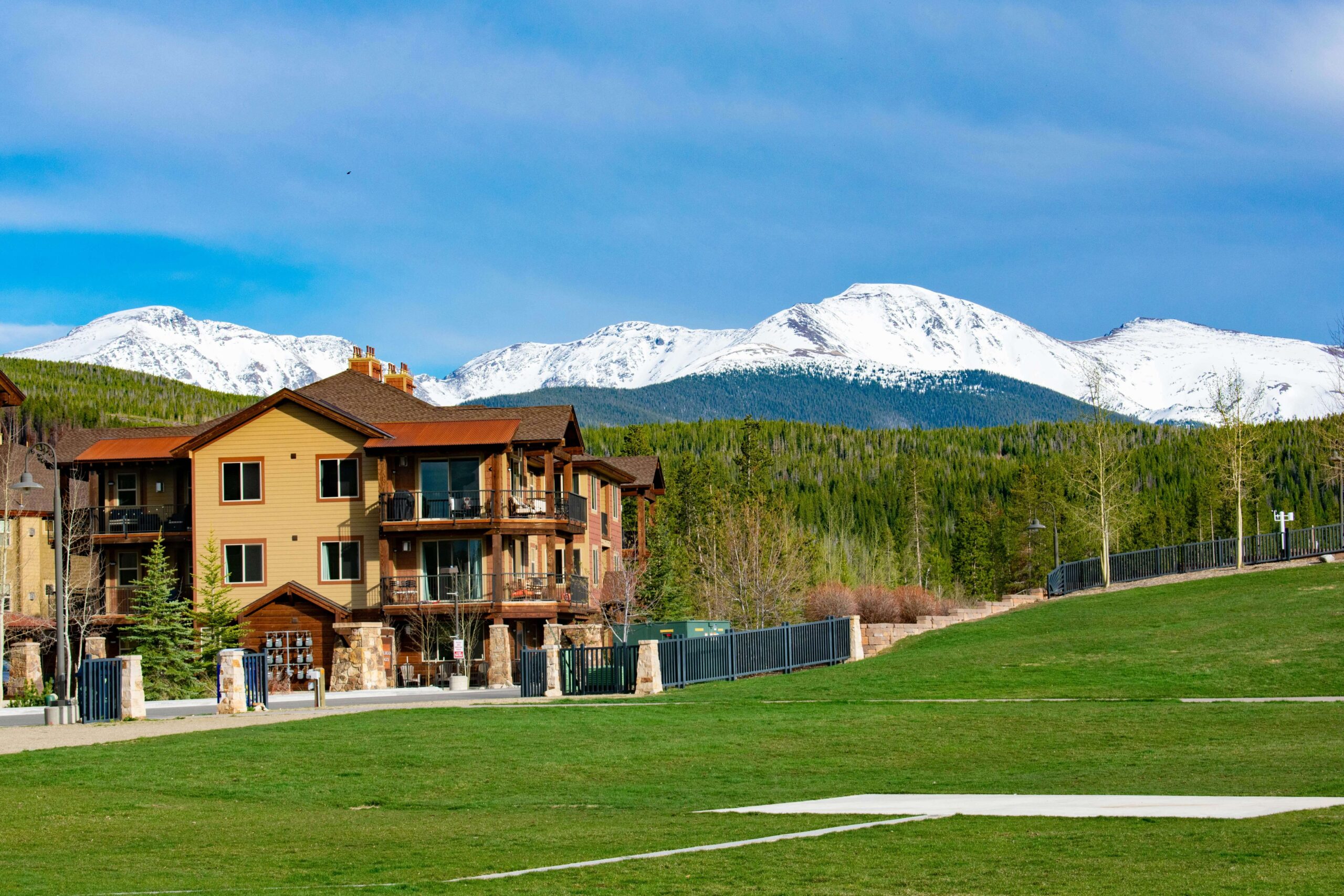 brown house near grass field with view of snow mountain in the day light
