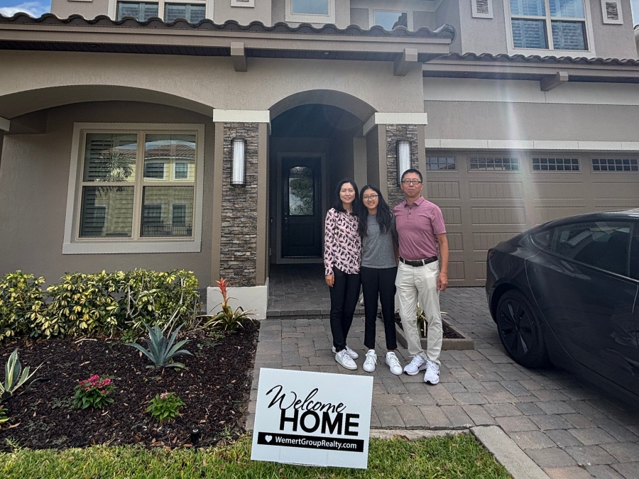 Fabiola Meneses' clients in front of their house at closing! Sign says Welcome Home