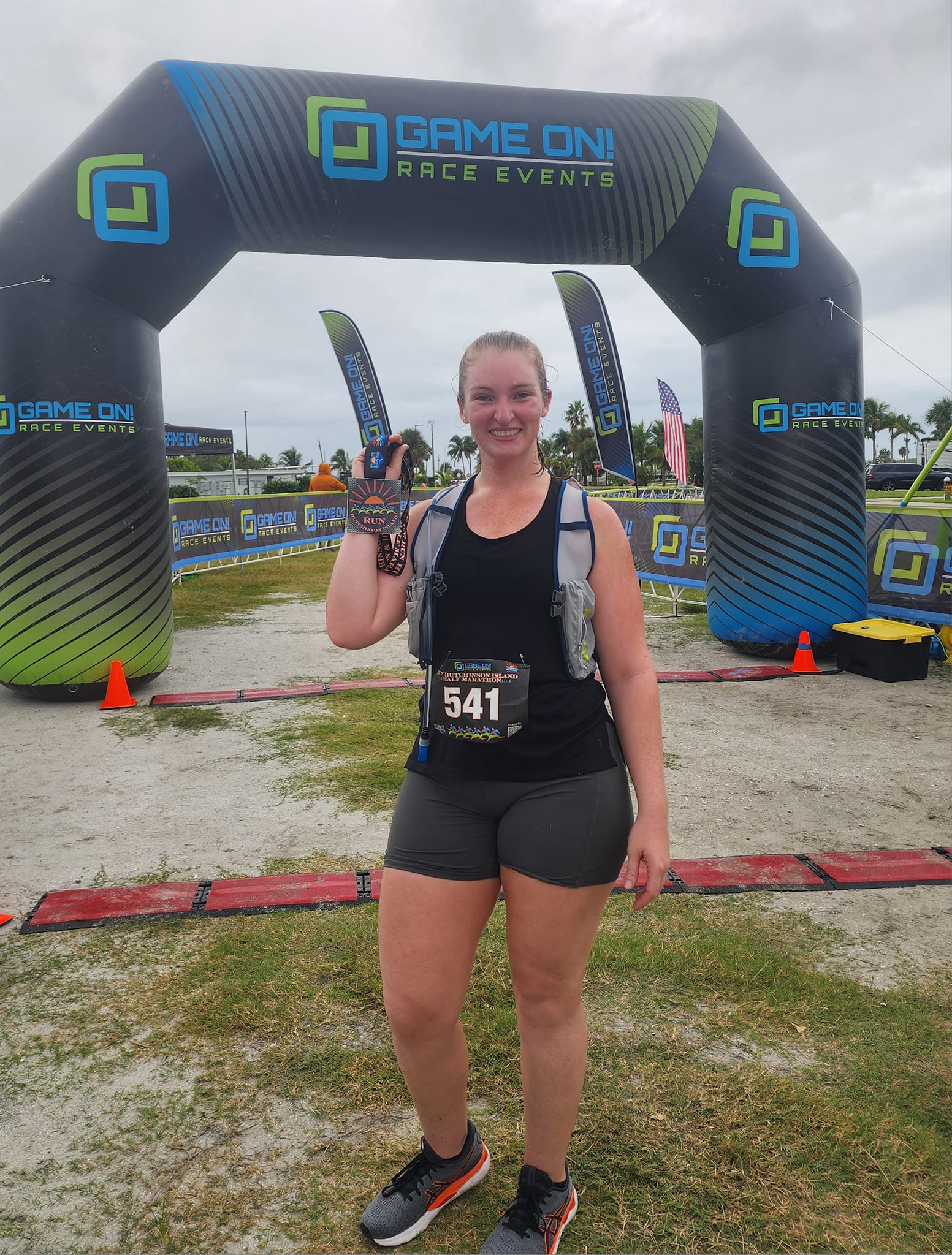 Orlando Realtor® Jessica Wicker smiles at the finish line of a Game On Race event, proudly holding her medal after completing the race.<br />
