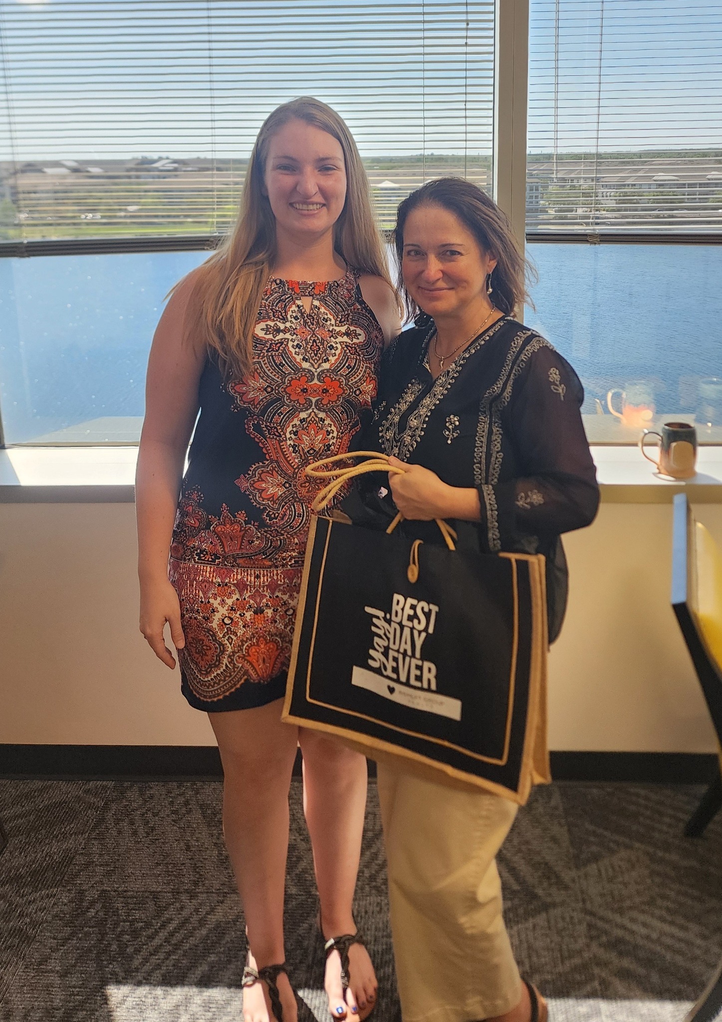 Orlando Realtor® Jessica Wicker stands with her client on closing day, celebrating with a Wemert Group Realty “Best Day Ever” gift bag.