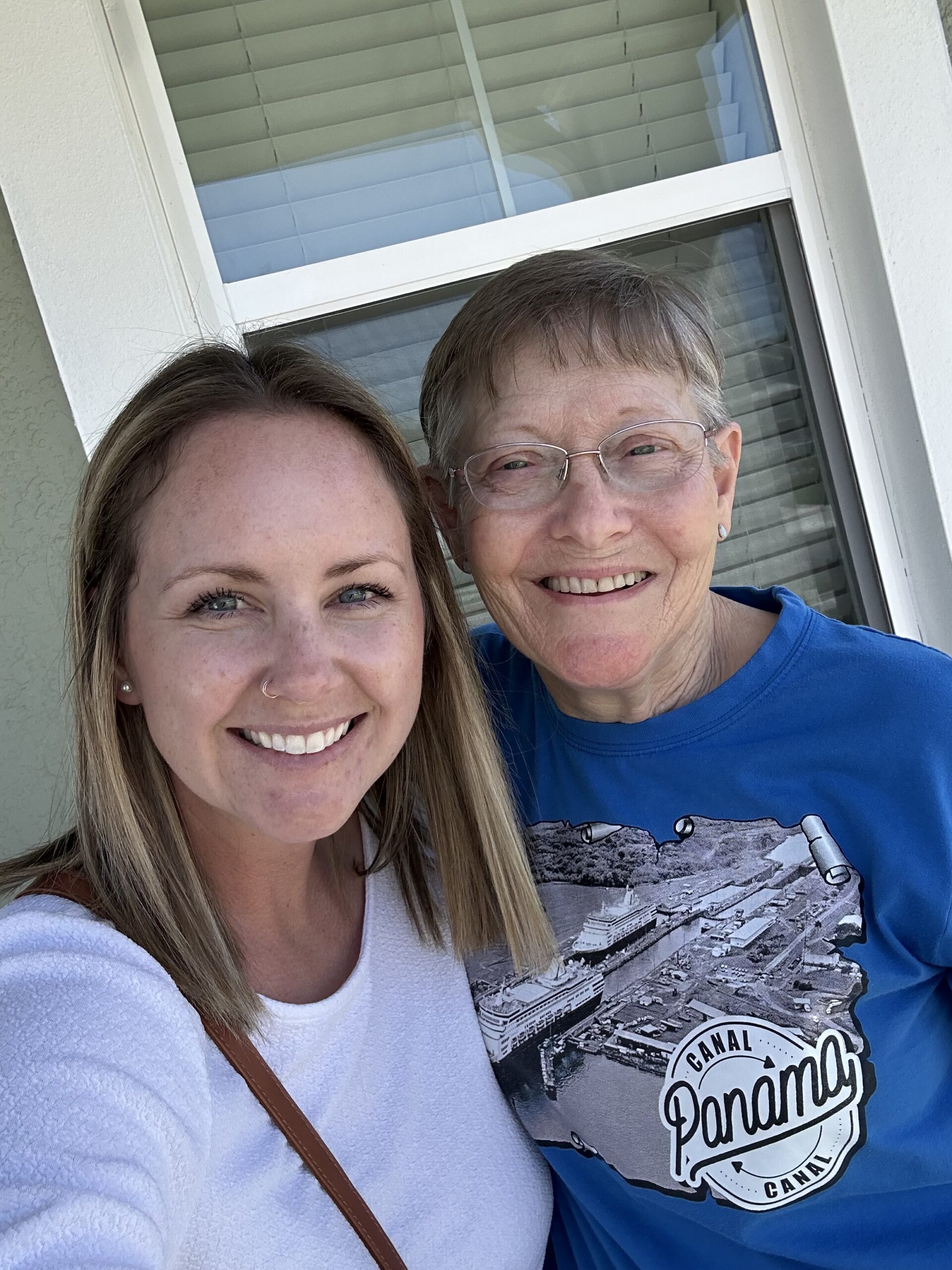 Tiffany Jolly smiles beside an older woman outside a home, standing together in natural light with a warm, friendly feel.
